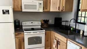 A kitchen with wooden cabinets, a white refrigerator, a microwave, a stove, and a dishwasher.