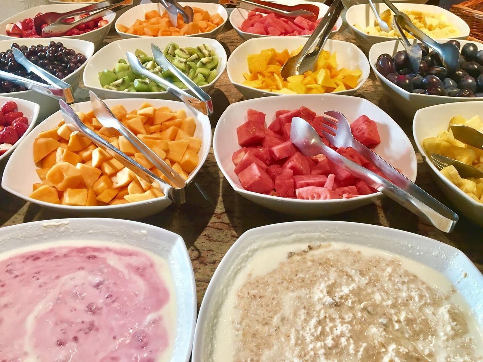 Un bufé con diversas frutas y postres.