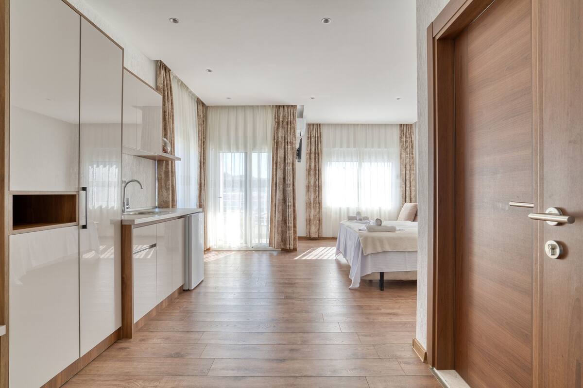 A modern kitchen with wooden flooring, a built-in oven, and a dining area with a table and chairs.