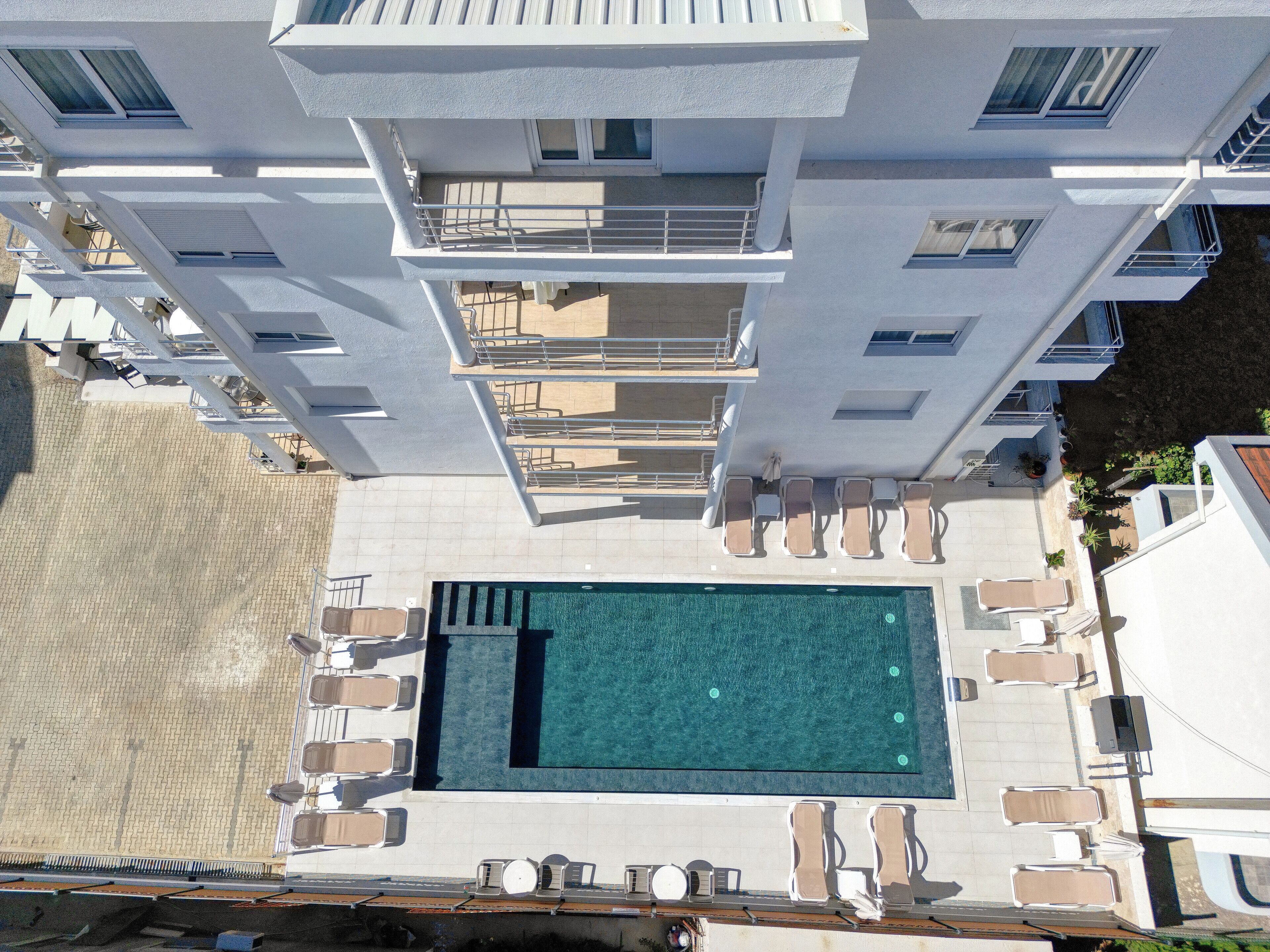 Una piscina en la azotea con tumbonas y vistas de los edificios circundantes.