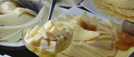 A buffet with various dishes including sliced apples, cheese, and other prepared foods.