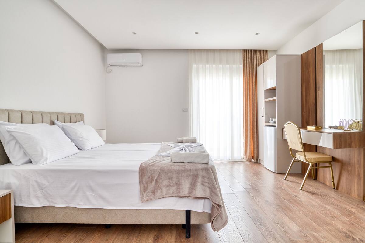 A modern bedroom with a large bed, a desk, and a chair.