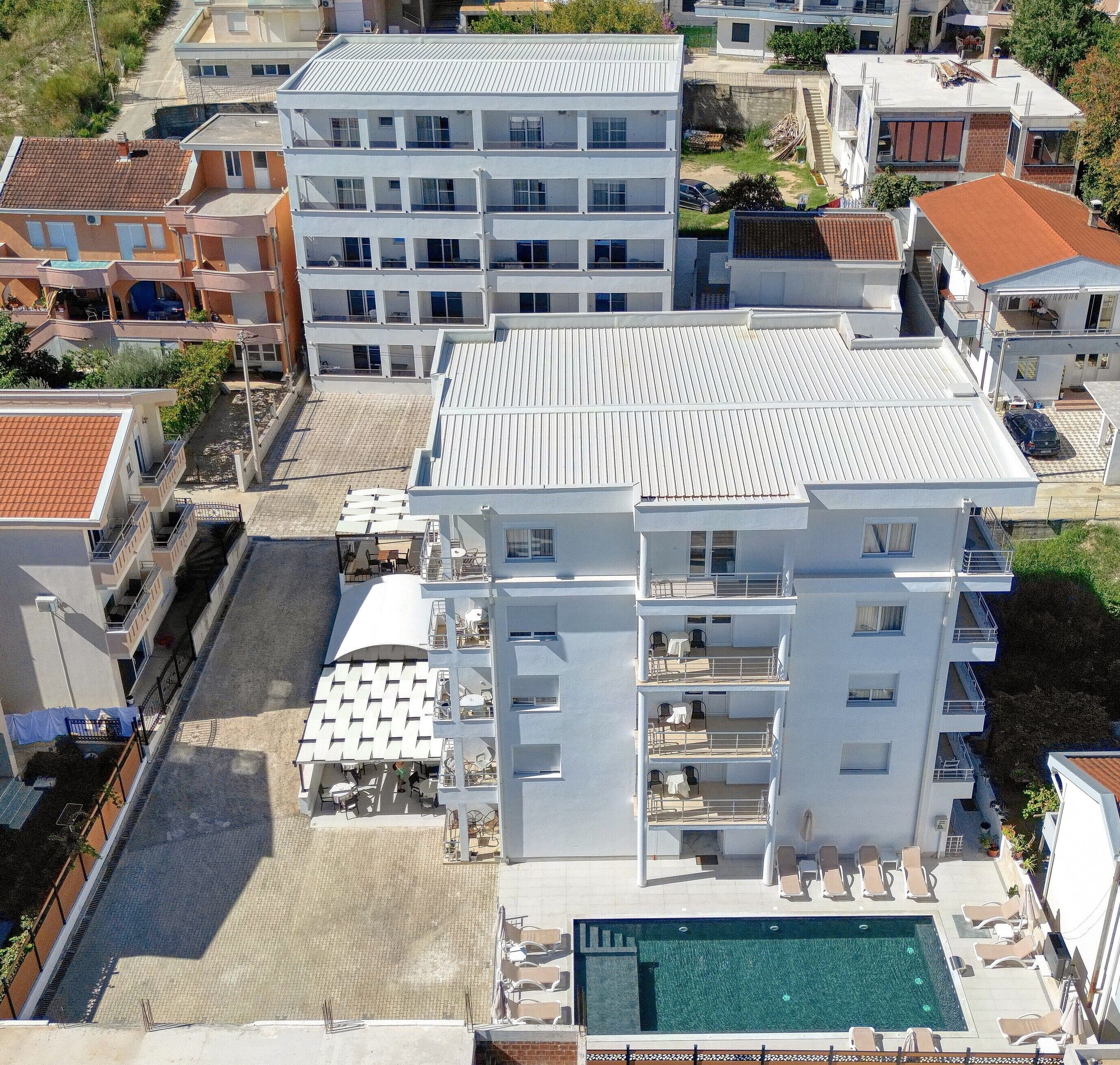 Ein mehrstöckiges Hotel mit Pool auf dem Dach und einer Außenbereich-Sitzgelegenheit.