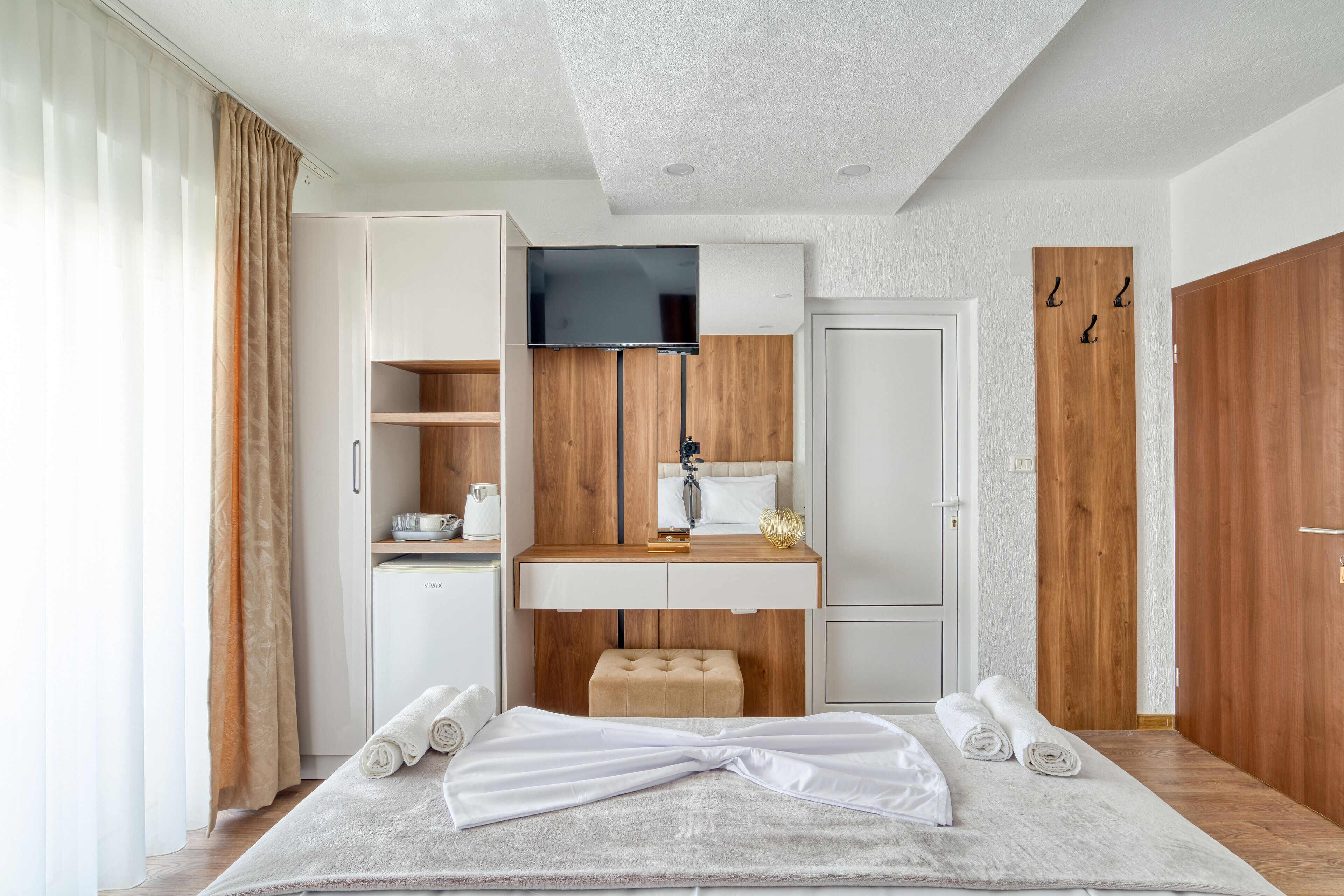 Habitació d'hotel moderna amb un llit, televisió, escriptori i armari.