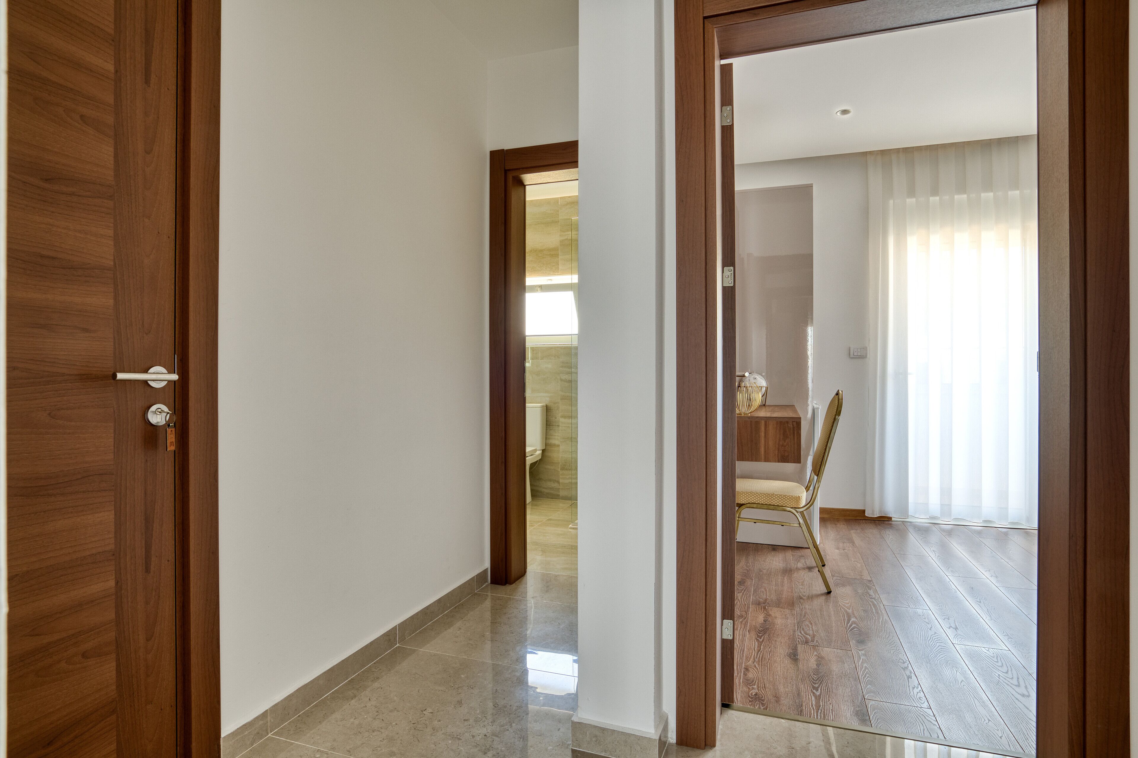 Un pasillo que conduce a un comedor con piso de madera y una silla.