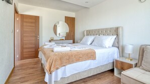 A bedroom with a large bed, a bedside table with a lamp, a wooden door, and a mirror on the wall. - Aqua Lounge Aparthotel Ulcinj (Ulcinj)