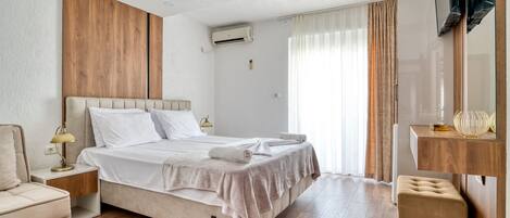 A modern hotel room with a large bed, a wooden accent wall, a flat-screen TV, and a small seating area.