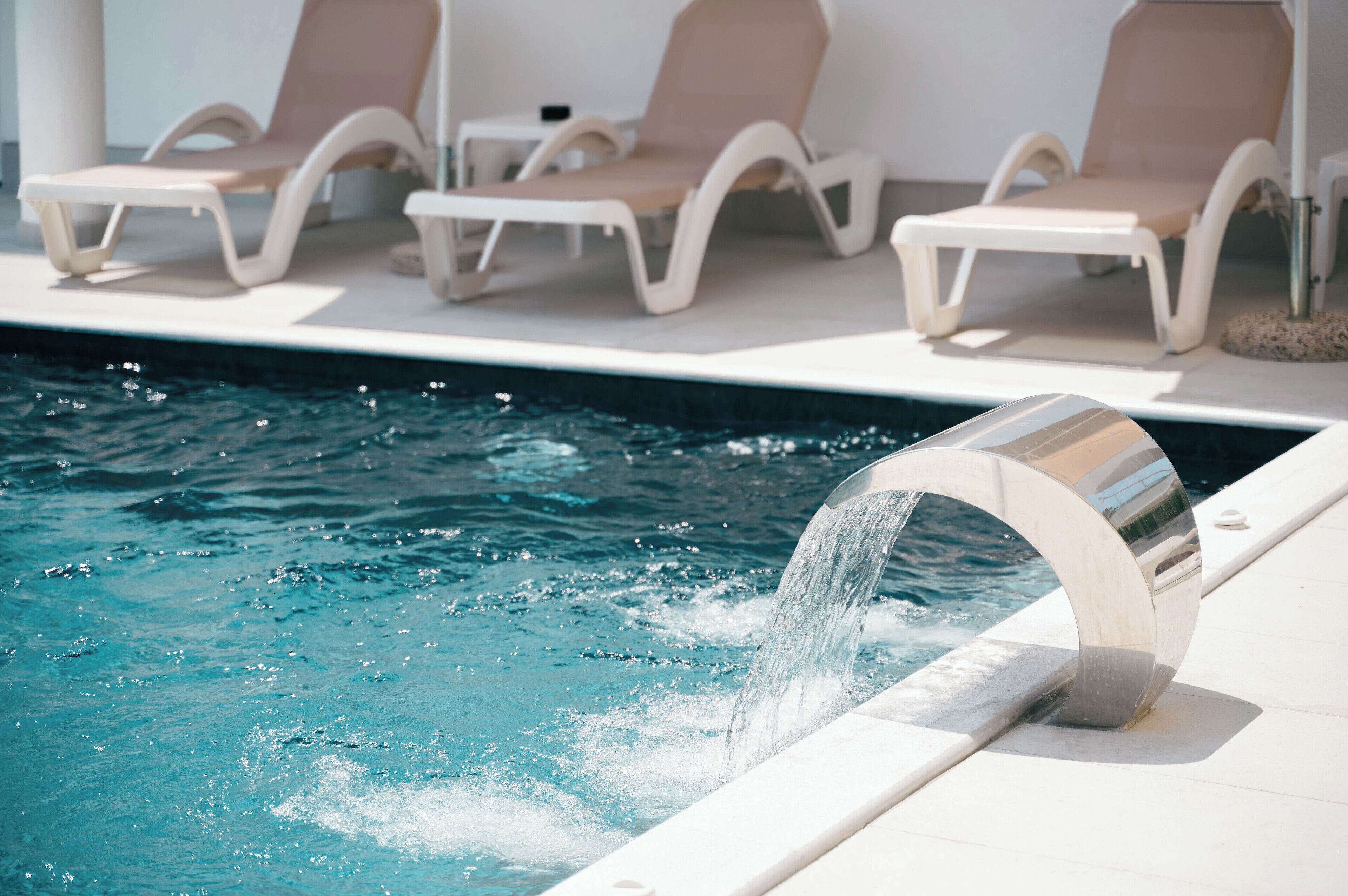 A pool area with lounge chairs and a water feature.