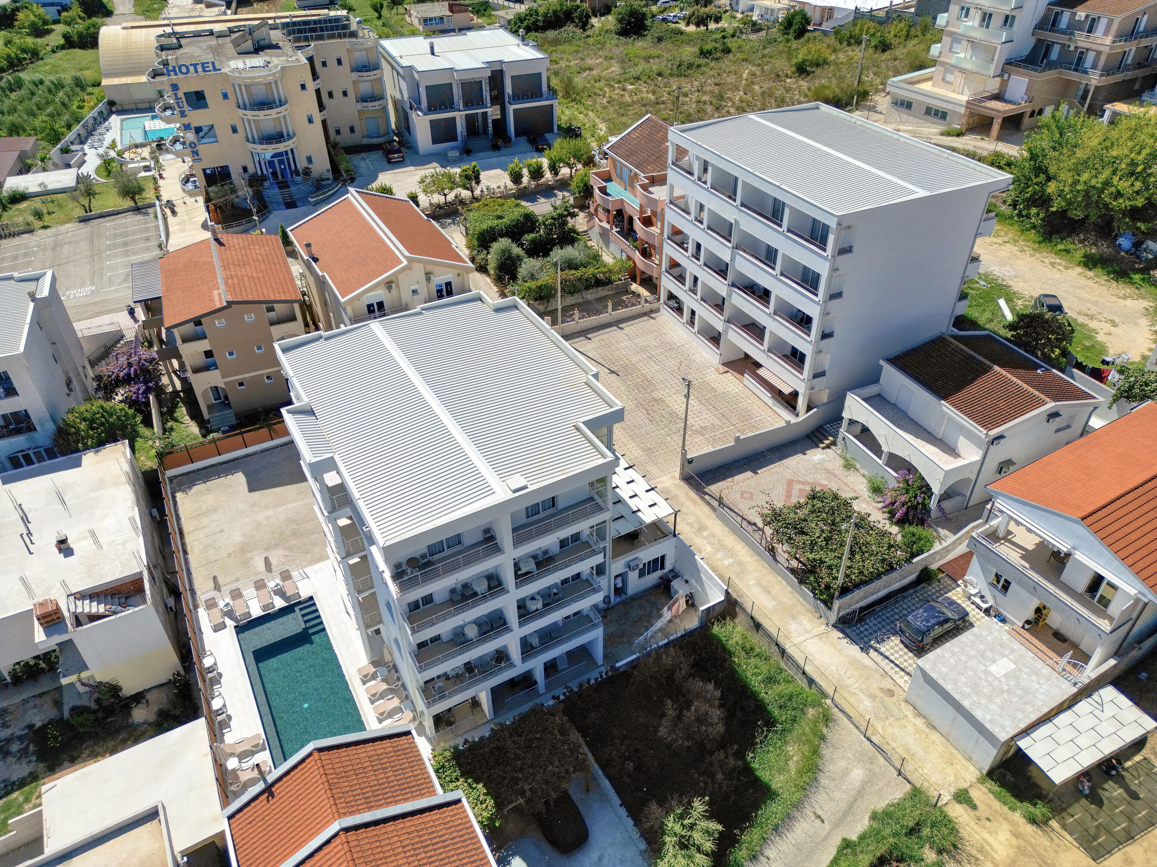 Um hotel com vários andares, piscina no terraço, várias varandas e área de estacionamento.