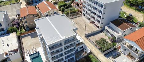 Um hotel com vários andares, piscina no terraço, várias varandas e área de estacionamento.