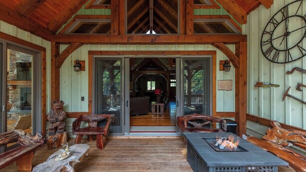 L’intérieur d’un chalet rustique, avec des poutres en bois, une cheminée en pierre et une grande horloge au mur.