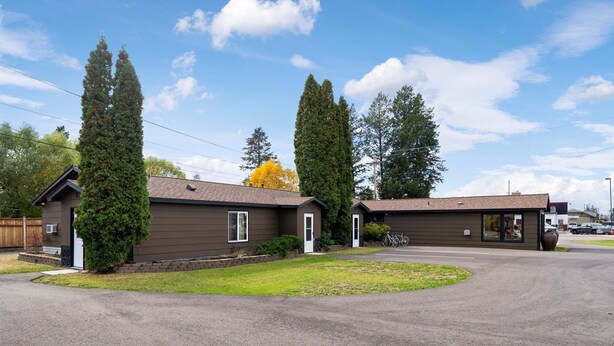 A row of two-story buildings with a central driveway, surrounded by tall trees and a clear sky. - Peaceful 1BR Escape Near Glacier National Park (Columbia Falls)