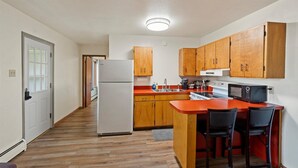 A compact kitchen with wooden cabinets, a refrigerator, a microwave, and a sink. - Peaceful 1BR Escape Near Glacier National Park (Columbia Falls)