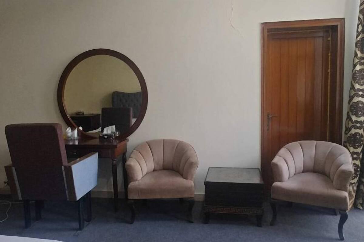 Ein Zimmer mit einem Schreibtisch, zwei Sesseln, einem runden Spiegel und einer Holztür.