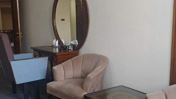 Een kamer met een stoel, een tafeltje, een spiegel en een bureau.