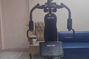 Un gimnasio con una bicicleta estática, una banca y una máquina de ejercicios instalada en la pared.