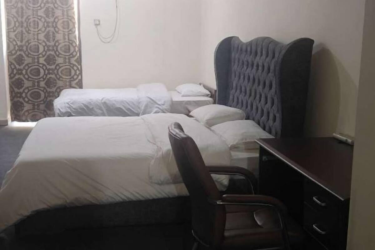 Ein Hotelzimmer mit einem Bett, einem Schreibtisch, einem Stuhl und einem Vorhang mit Muster.