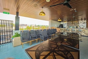 Ein Außenbereich mit Sitzgelegenheiten, einer Bar, Holzbalkendecke und Blick auf die Stadt.