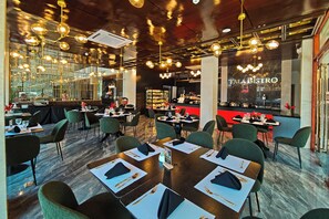 A restaurant interior with tables set for dining, a bar area, and a view through a large window.