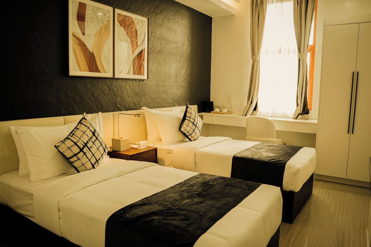 Habitación de hotel con dos camas, un escritorio y un armario.
