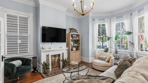 Una sala de estar con chimenea, televisor, sofá y candelabro.