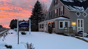 A two-story building with a snow-covered roof and a sign for Allegory Inn. - Allegory Inn (Carroll)