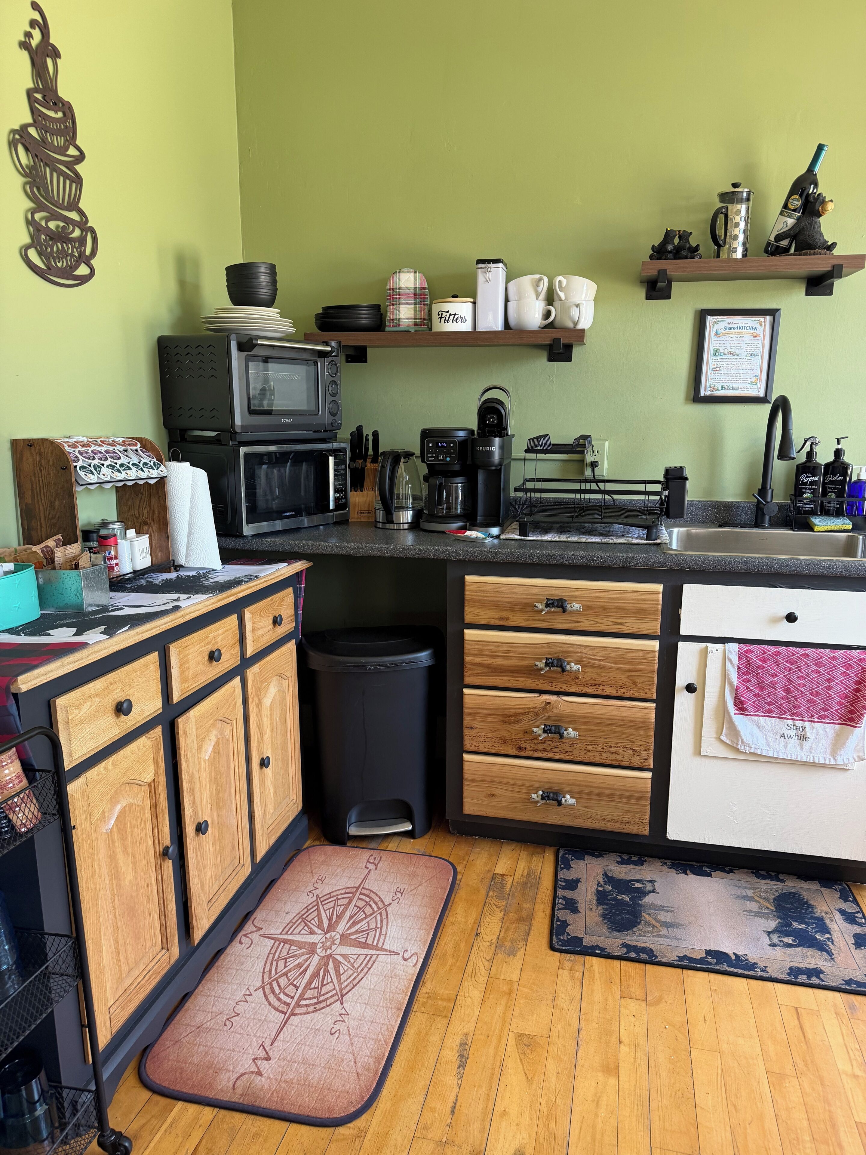 A compact kitchen with a microwave, coffee maker, and a small trash bin.