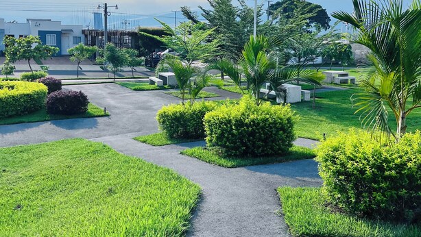 A landscaped area with pathways, greenery, and buildings in the background. - Nala House  (Nuevo Sitio del Nino)