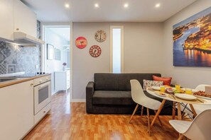 Uma cozinha moderna com área de refeições, um sofá e um quadro na parede.