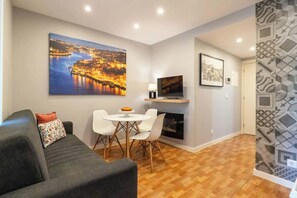 Un salon moderne comprenant un canapé, une table à manger avec des chaises, un téléviseur à écran plat et une cheminée.