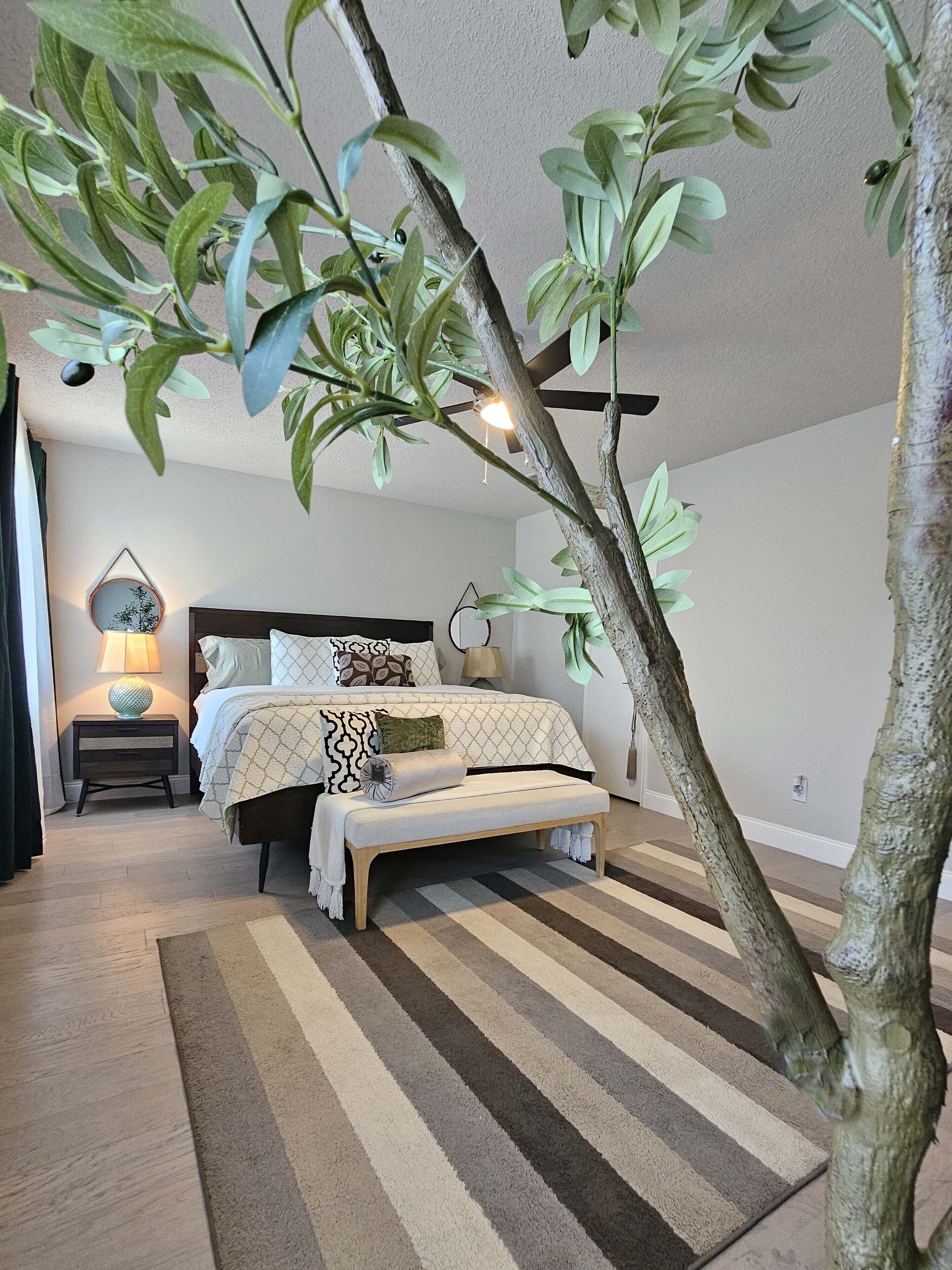 Une chambre à coucher avec un lit, des tables de chevet et un grand arbre artificiel.