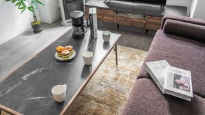 A modern living room with a coffee table, a sofa, a television, and a potted plant. - BELLE NEIGE 305 (Sapporo)
