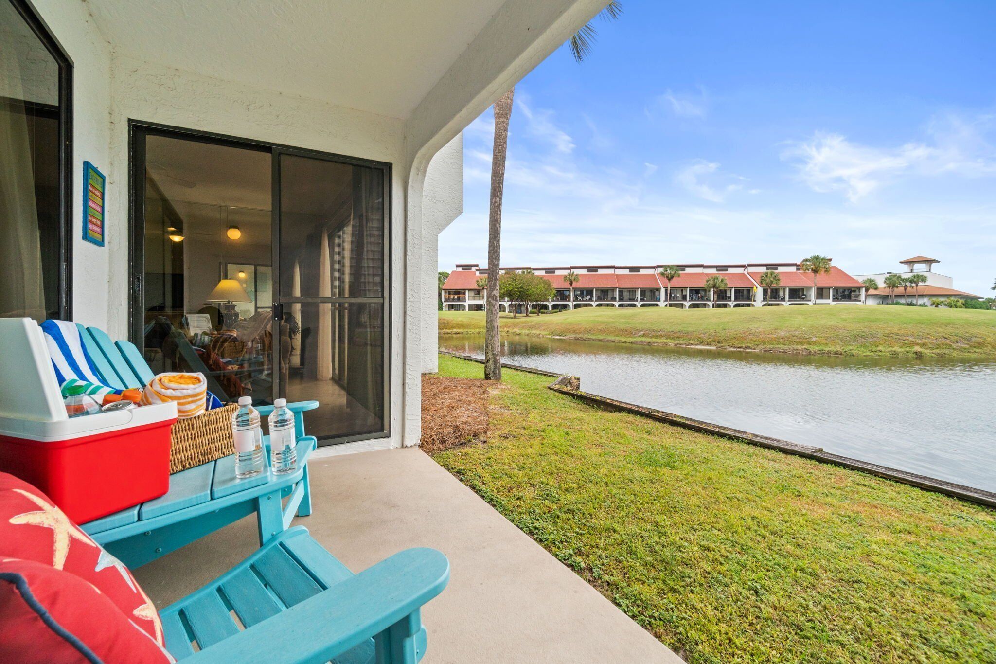 A covered outdoor seating area with a pool view, a red cooler, and a wicker basket.
