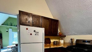 A kitchen with wooden cabinets, a white refrigerator, a stove, and a wooden countertop.