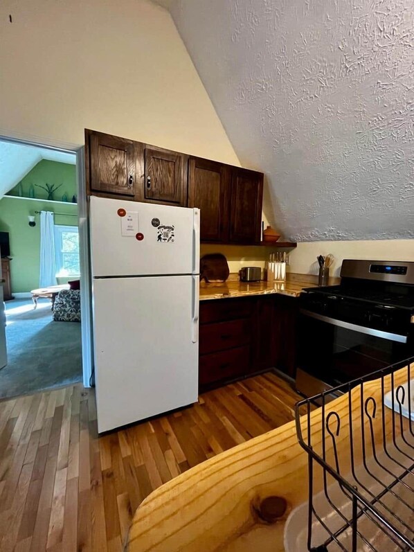 Une cuisine avec des meubles de rangement en bois, un réfrigérateur blanc, une cuisinière et un plan de travail en bois.