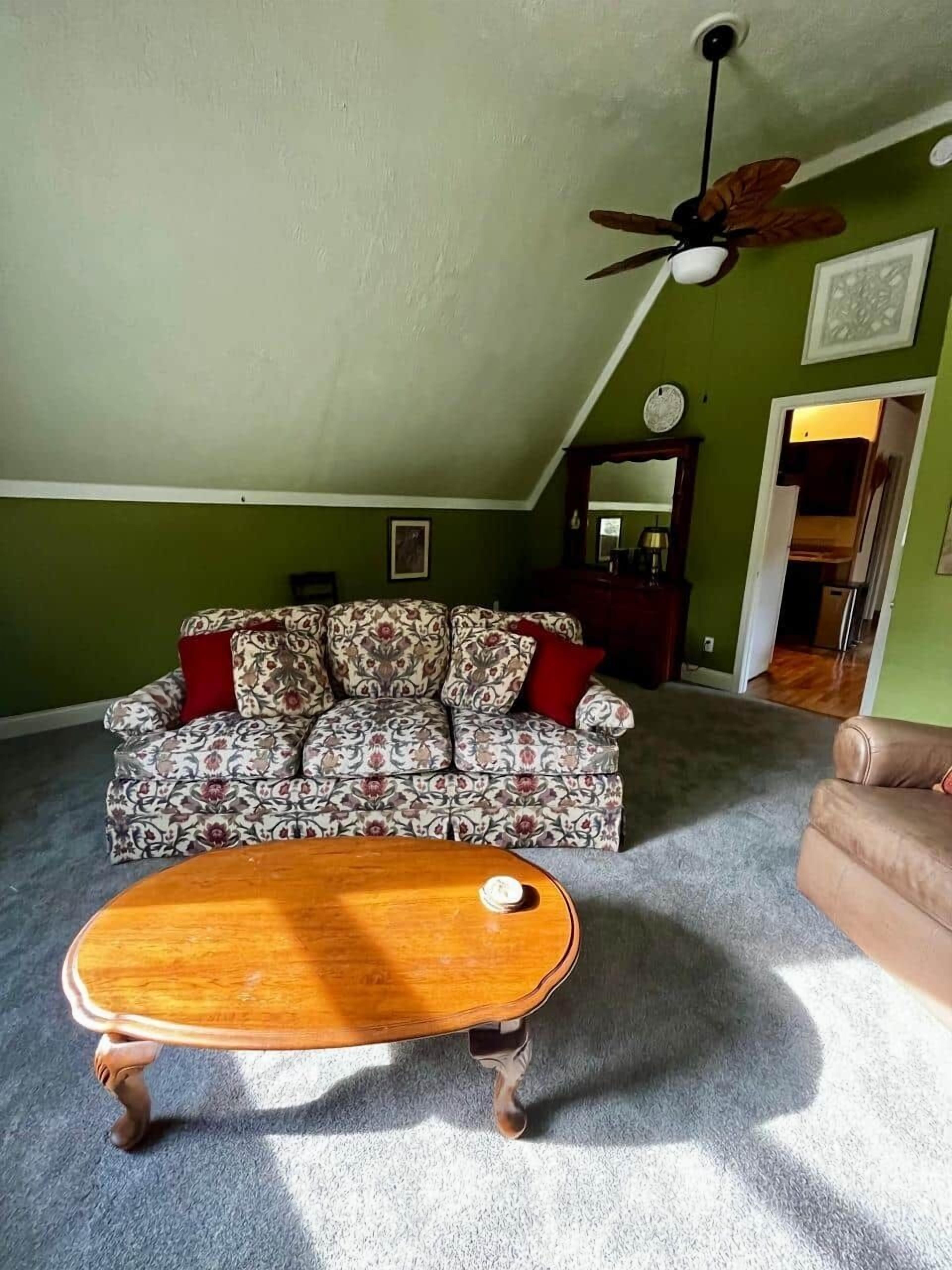 A living room with a patterned sofa, a wooden coffee table, and a ceiling fan.