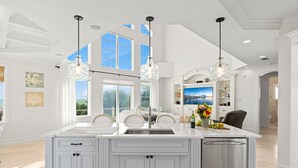 A spacious kitchen with a large island, white cabinetry, and pendant lighting. - 7791 Highway A1A (Melbourne Beach)