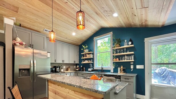 Une cuisine moderne avec un plafond en bois, des plans de travail en granit et un îlot central doté de sièges.