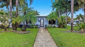 A house with a paved driveway leading to a front door, surrounded by palm trees and well-maintained grass. - Fort Lauderdale Escape With Pool, Hot Tub & Dual Kitchens Paradise Stay by Avantstay (Fort Lauderdale)