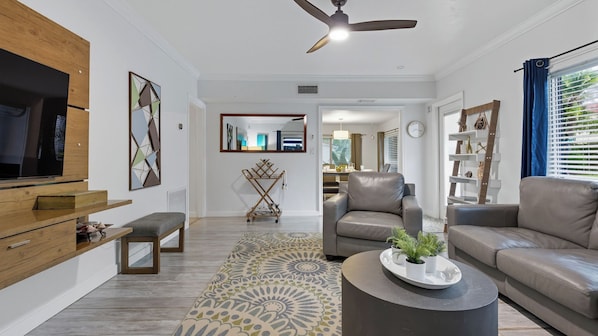 A modern living room with a flat-screen TV, two sofas, a coffee table, and a ceiling fan. - Fort Lauderdale Escape With Pool, Hot Tub & Dual Kitchens Paradise Stay by Avantstay (Fort Lauderdale)
