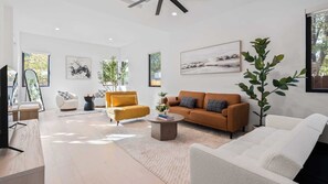 A modern living room with a sofa, armchairs, a coffee table, and artwork on the walls. - Stylish Home With Firepit & Balcony Steps From Austins Best Near Rainey St, Lady Bird Lake & Downtown The Ashlee by Avantstay (Austin)
