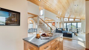 Un espacio habitable amplio con una escalera de madera, una mesa de comedor con sillas y un ventanal con vistas al exterior.