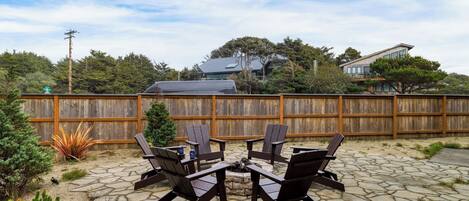 A patio with a stone floor, wooden fence, and outdoor furniture.