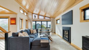 Una sala de estar moderna con un sofá modular, una chimenea y ventanas amplias que ofrecen vistas al exterior.