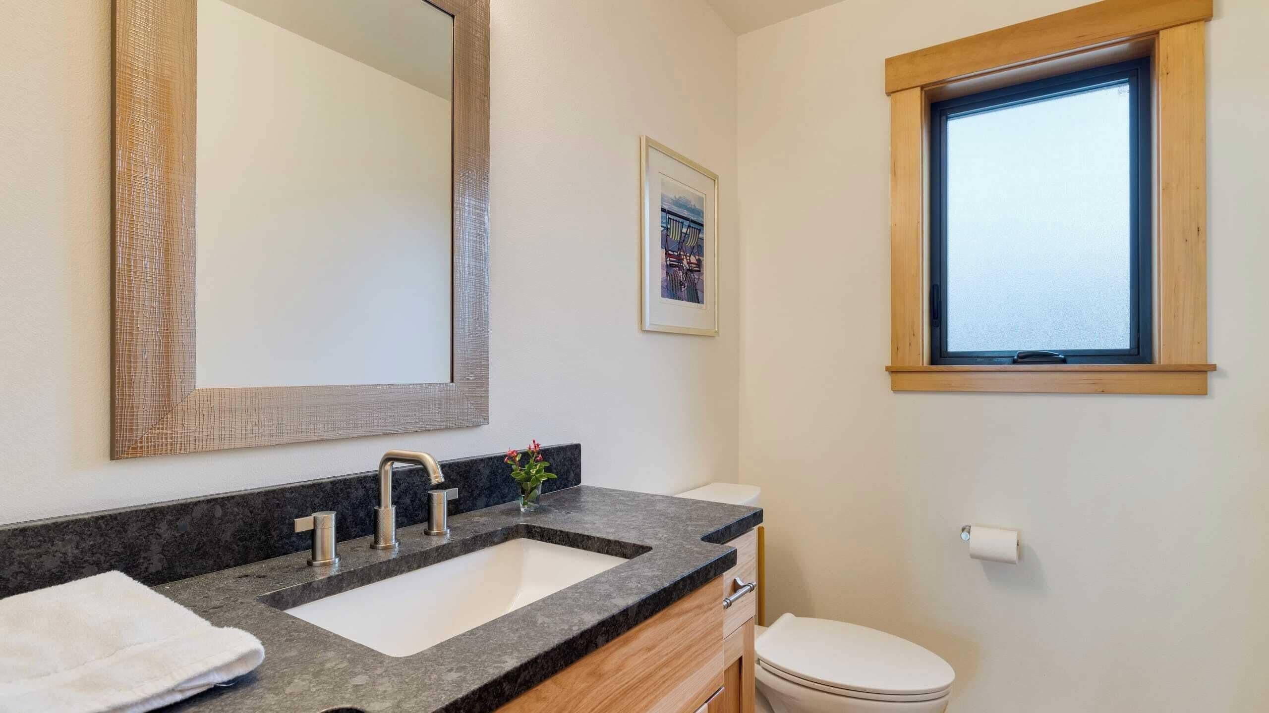 Ein Badezimmer mit Waschbecken, Spiegel, Toilette und Fenster.