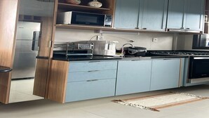 A kitchen with light blue cabinets, a black countertop, a microwave, a coffee maker, and a stove.