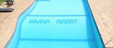 A swimming pool with 'KHWE5A RESORT' written on the water.