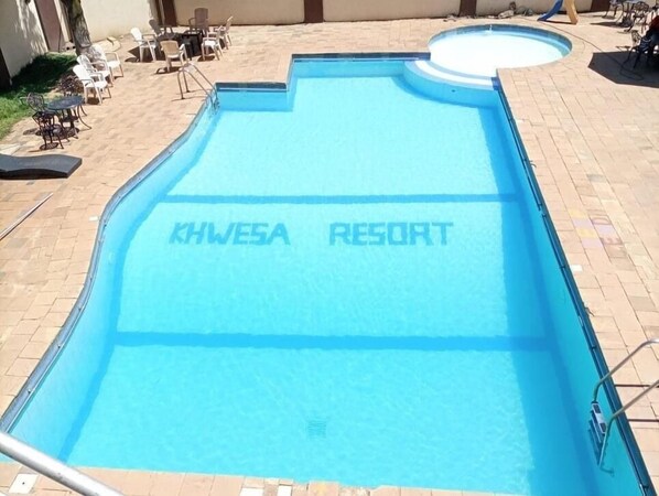 Uma piscina com a inscrição 'KHWE5A RESORT' na água.
