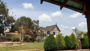Uma casa com telhado inclinado, chaminé visível e um gramado bem cuidado com um caminho de pedra que leva à entrada.