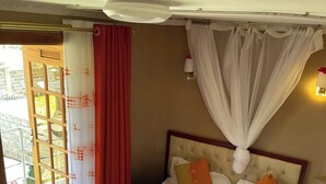 Quarto de hotel com cama, cortinas, dossel e vista para o exterior.